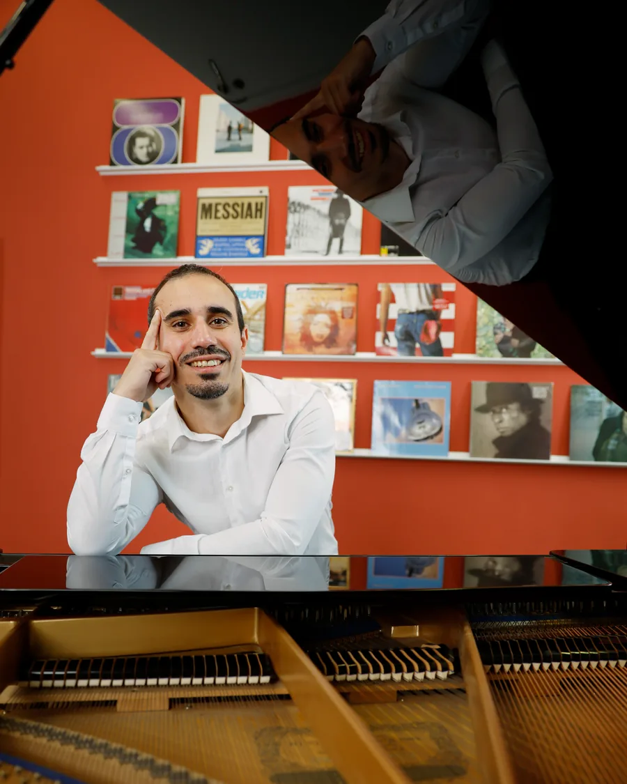 Pianist Ivan stützt den Kopf in die Hand und lächelt am Flügel