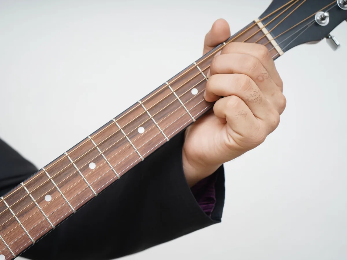 Finger üben einen Griff auf dem Griffbrett einer Gitarre