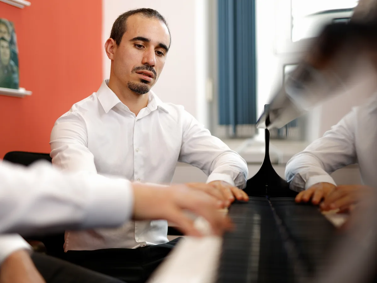 Pianist Ivan spielt am Flügel, im Vordergrund seine Hände auf den Tasten