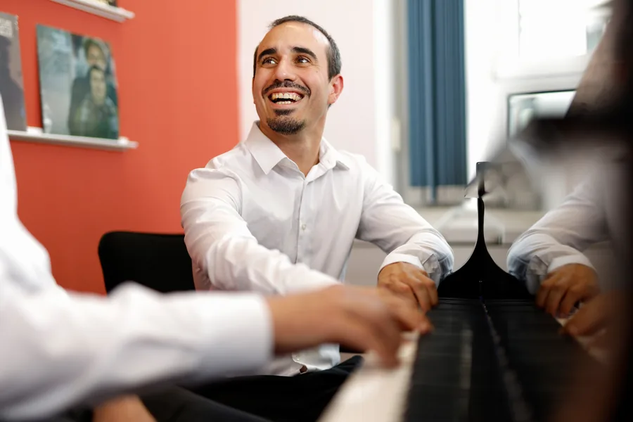 Der Pianist Ivan mit den Händen auf den Tasten eines schwarzen Flügels